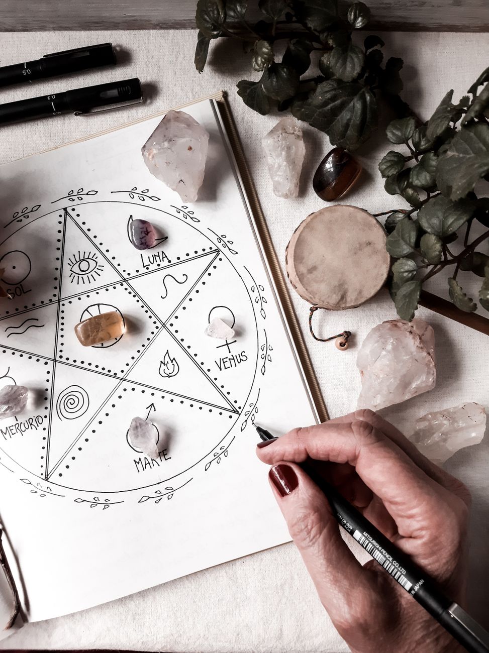 woman drawing on a white paper with crystals